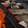 Fillets of salmon sit on a grill as a fire burns below them